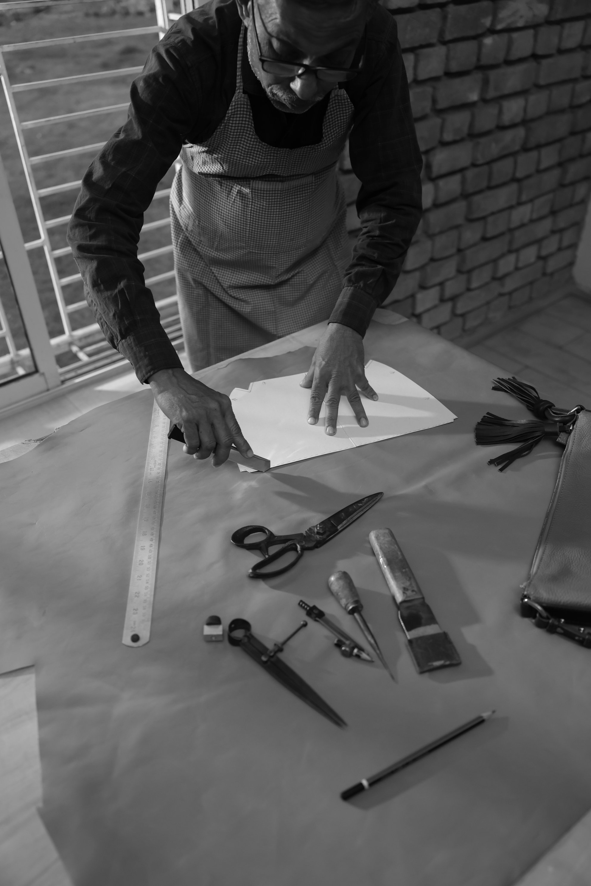 Skilled artisan pattern-making and cutting leather components with precision instruments